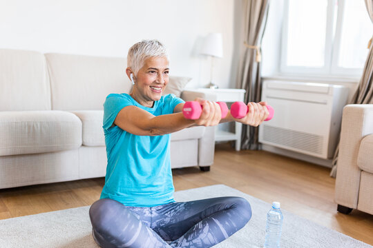 Senior woman exercise with dumbbells at home . happy mature woman doing arm workout using dumbbells. Elderly woman prefers healthy lifestyle