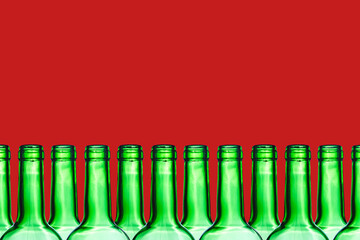 Green wine bottle. Empty glass isolated on red. Set of blank no label wine bottle in a row. Winery shelf texture. Alcohol background. Shiny transparent vibrant color panoramic view.