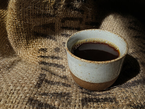 Hot Coffee in Traditional Ceramic Cup on Vintage Coffee Beans Sack