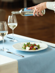 Spanish tomato salad and waiter pouring white wine