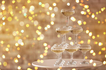 Tower made of glasses with champagne on table against blurred lights © Pixel-Shot