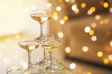 Tower made of glasses with champagne on table in room