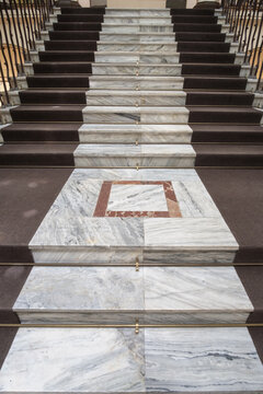 Old marble stairs with dark brown carpet