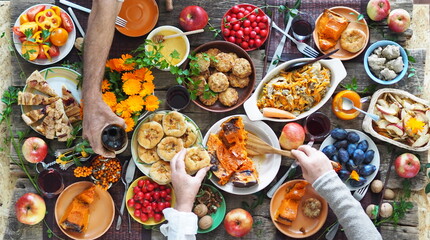 Country style. Thanksgiving table. A lot of food. The guests is hands hold wine over the set table. View from above.