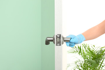 Woman wearing medical glove to open door