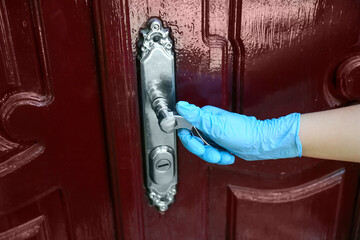 Woman wearing medical glove to open door