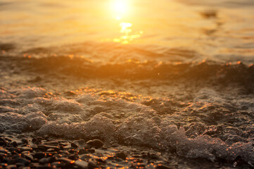 Sea surf on sunset time. Black Sea coast. Pebble washed by sea waves.