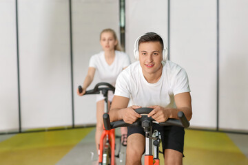 Fototapeta na wymiar Young man training on exercising bike in gym