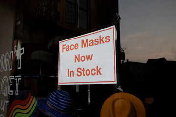 COVID 19 mask face coverings in stock sign for shoppers in retail store window