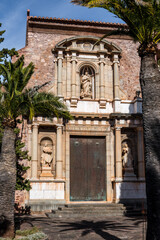 iron door to a large stone monastery that is located in the mountains between palm trees