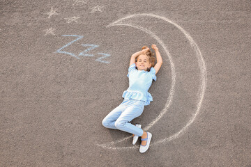 Little girl lying near chalk drawing of moon outdoors