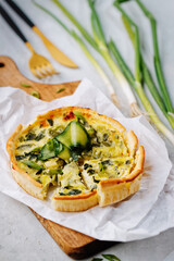 Leek vegetarian tart with cheese on wooden cutting board. Quiche with leek and cheese.