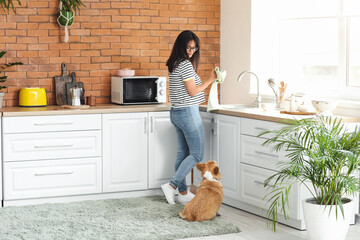 Woman with cute corgi dog in kitchen at home