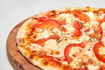 Pizza with bacon, bell pepper, tomatoes and cheese on wooden board. Close-up, selective focus
