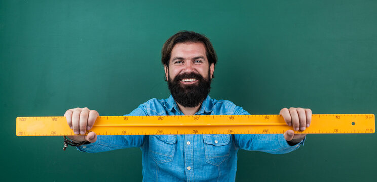 bearded man work in classroom with ruler. prepare for geometry exam. college lecturer on math lesson. back to school. formal education. measure and size. happy mature teacher holding mathematics tool