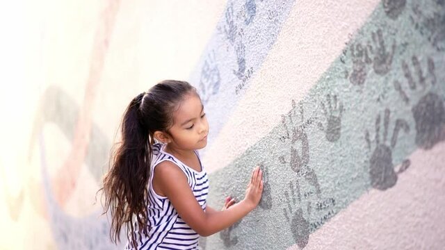 Cute little girl putting her hands on a hand wall painting