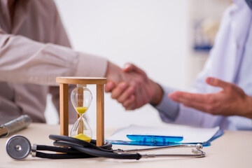 Old male patient visiting young doctor in time management concep