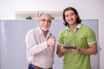 Old professor physicist and young student in the classroom