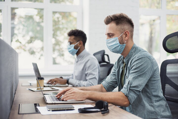 Obraz premium Young people professionals working in office wearing medical protective masks - Colleagues using laptops in coworking - Selfcare, coronavirus COVID-19 protection, social distancing, healthcare concept