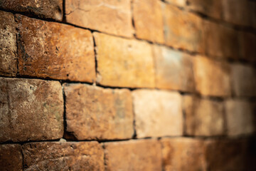 Side view of a backlit red orange shabby brick wall. Blurred focus