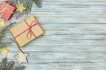 snowy fir tree branches, christmas paper gift boxes and glowing star lights on grey wooden background