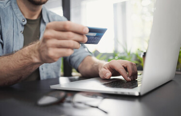 Man hand holding credit card and using laptop in office, Businessman or entrepreneur working, Online shopping, e-commerce, internet banking, spending money, working from home concept