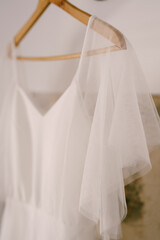 Close-up of the top of the bride's dress on a wooden hanger.