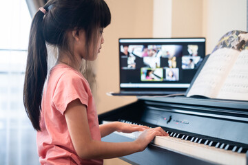 Homeschool Asian young girl learning piano from music online class.