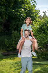 Happy father carrying son on his shoulders in the park