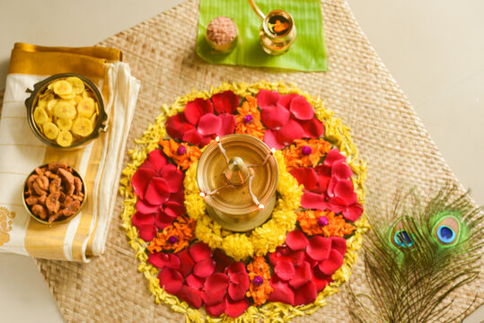 Women Lighting lamp and traditional flower bed for Onam, harvest festival of Kerala India. fresh flower carpet floral pattern made for Indian festival Vishu, dussehra, dasara, diwali celebration also.