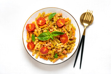 Fusilli - classic italian pasta from durum wheat with chicken meat, tomatoes cherry, basil in tomato sauce in bowl, spoon, fork on white wooden table Mediterranean cuisine Top view Flat lay