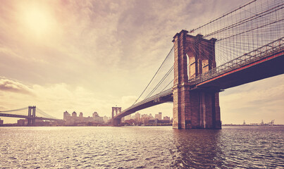 Vintage toned picture of Brooklyn Bridge against the sun, New York City, USA.