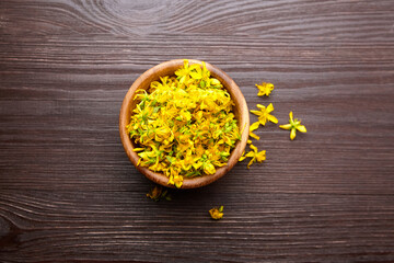 Hypericum perforatum or st johns wort plant flowers buds in wooden bowl on dark background
