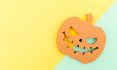 Halloween background idea.Flat lay wooden Jack o lantern spooky pumpkin on green yellow paper color background.Halloween design with copy space for text advertising.Background idea in Autumn October.

