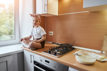 Little girl makes dough on kitchen.