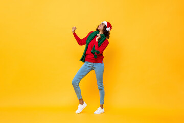 Fototapeta na wymiar Full length portrait of fun happy woman in Christmas attire dancing on isolated yellow studio background