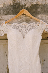 Close-up of a bride's wedding dress with lace on a hanger.