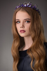 portrait of a beautiful blonde teenager girl with exquisite makeup in a stylish black dress