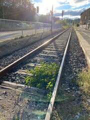 Bahngleise führen in den Horiznt die Sonne scheint entgegen bei blauem Himmel mit weißen Wökchen