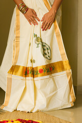 Traditional white silk sari / saree with golden details, woman use to wear on Onam, Diwali festival Kerala India. pleated Kerala set saree. Indian silk sari