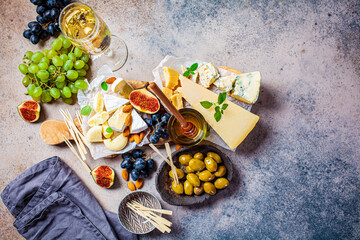 Naklejka na ściany i meble Cheese plate served with fruits, honey and snacks, top view. Assorted cheese background.