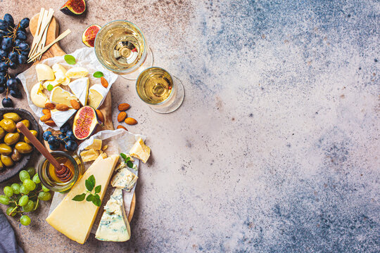 Cheese plate served with fruits, honey and snacks, top view. Assorted cheese background.