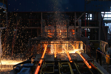 Red hot steel metal billets after molten steel casting.  Continuous casting machine. Background of...