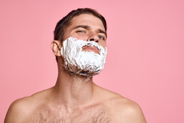 man with razor and white foam on his face pink background nude torso bathing treatments
