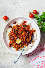 Chili con carne with rice in white bowl. Beef stew with beans in tomato sauce and rice. Traditional Mexican food concept.