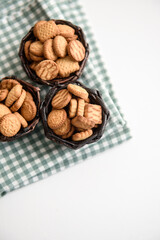 Small cracker cookies in a basket on a linen napkin on a white background