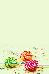 Colorful lollipops and confetti on yellow background. Sweets for party. Sugar