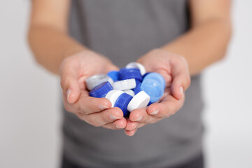 recycling and reuse concept - close up of plastic bottle caps in male hands for recycling to conserve the environment