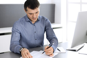 Businessman working with computer in modern office. Headshot of male entrepreneur or company...