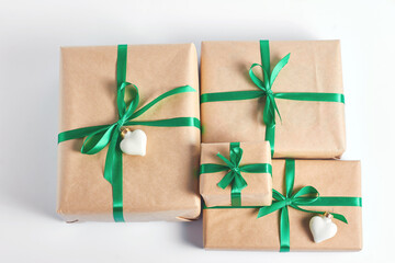 a stack of gift boxes wrapped in craft paper and decorated with green satin ribbon. Christmas concept. top view